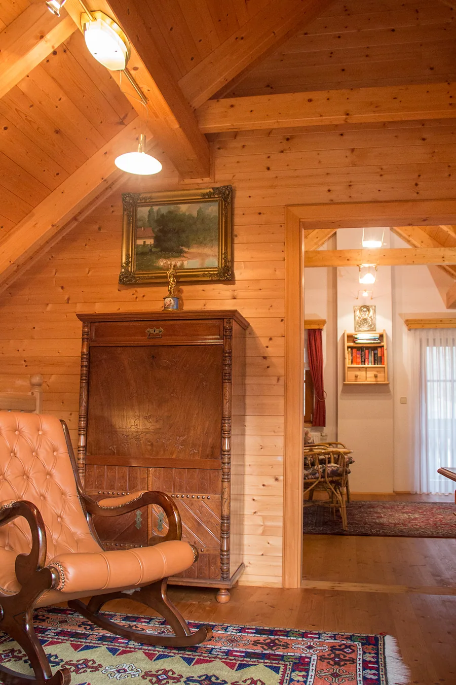 Dachzimmer mit Holzvertäfelung, Bauernkasten und Lederschaukelstuhl