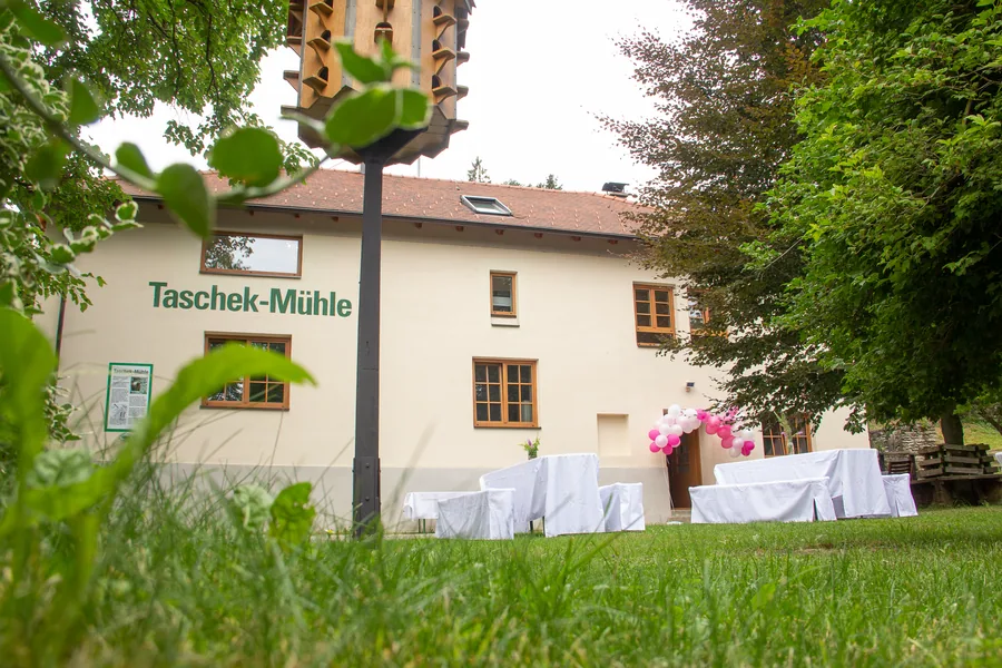 Die Taschek-Mühle mit festlich gedeckten Tischen im Garten und einem Taubenkobel