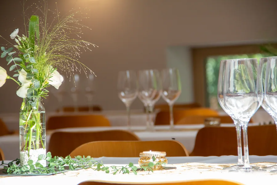 Weingläser und ein Blumenstrauß auf einer gedeckten Tafel