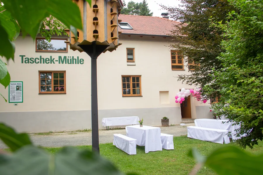 Die Taschek-Mühle mit gedeckten Tischen im Garten und einem Taubenkobel
