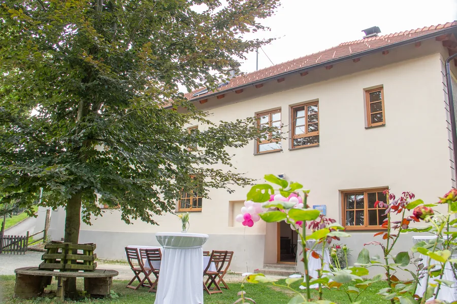 Die Taschekmühle mit Stehtischen und Rosen im Garten